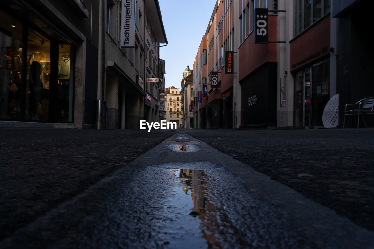 EMPTY ROAD AMIDST BUILDINGS IN CITY