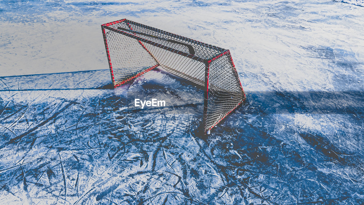 Red edged net on outdoors ice arena with hockey stick 