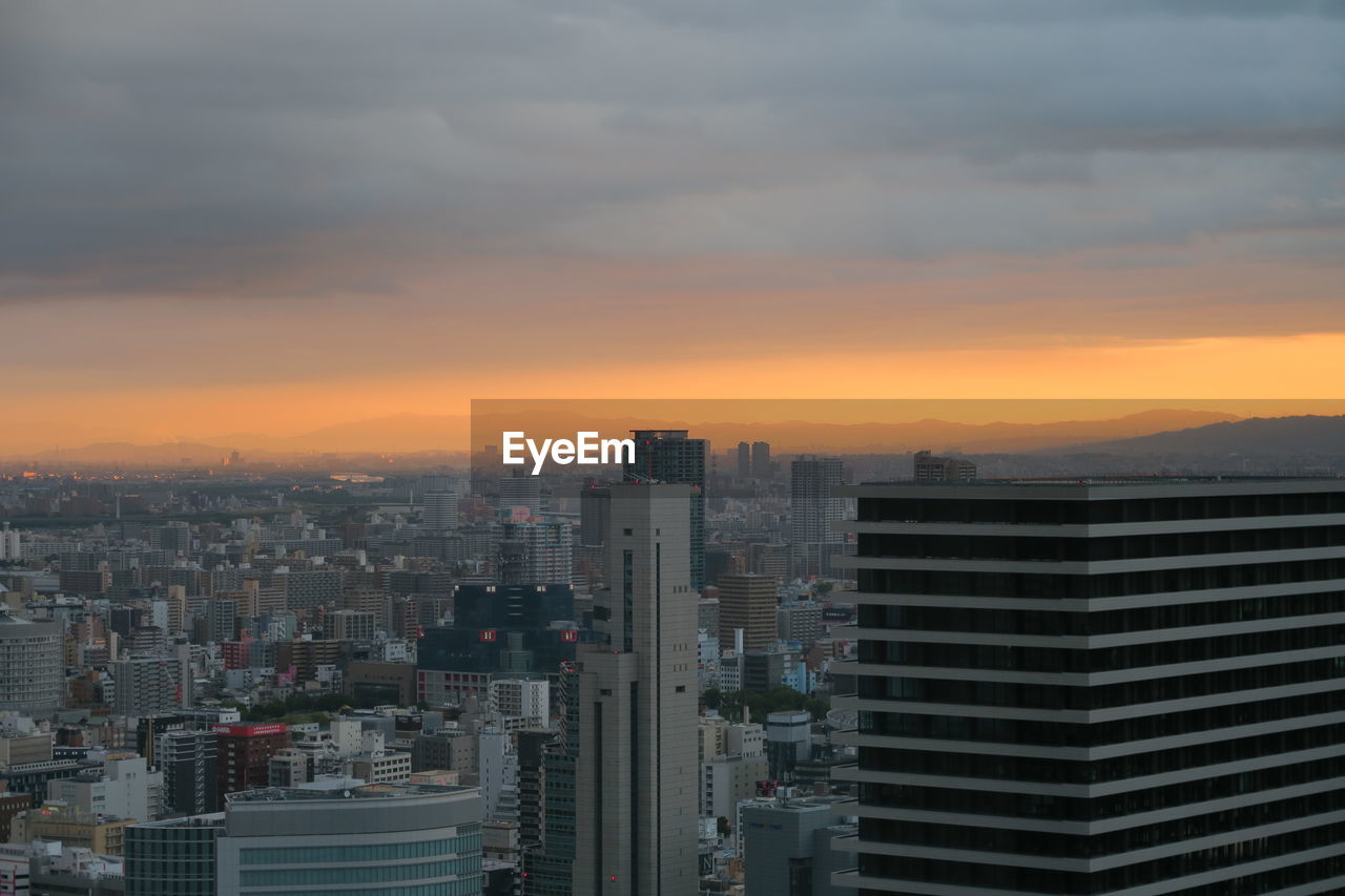 Modern buildings in city against sky during sunset