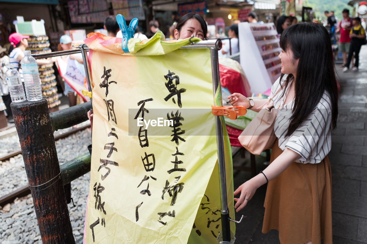 WOMAN HOLDING TEXT AT MARKET