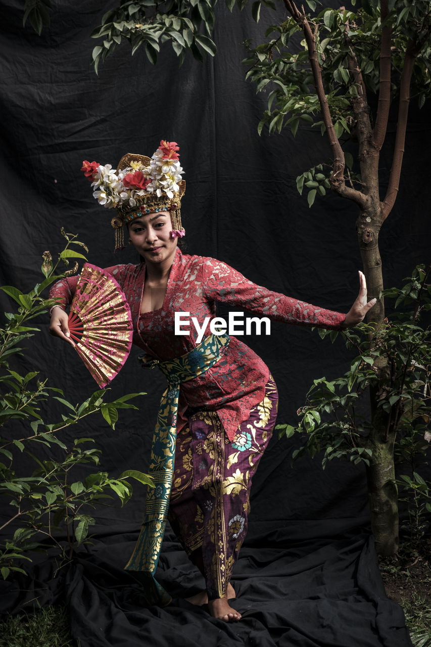 Woman in traditional clothing holding hand fan while dancing