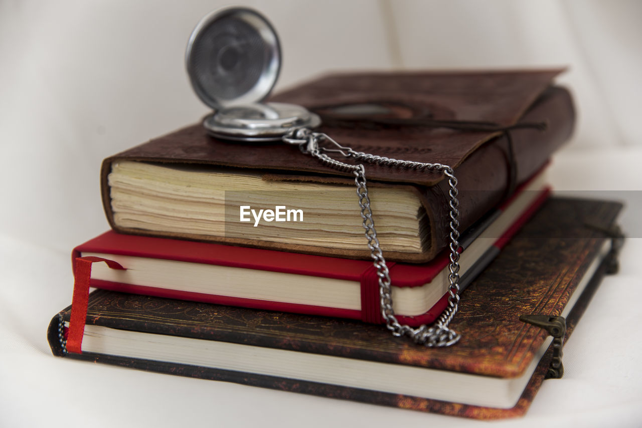 High angle view of pocket watch over books stack on table