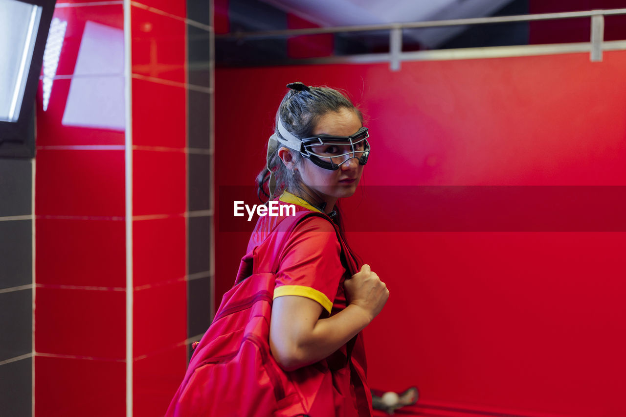 Lacrosse player with backpack standing in locker room