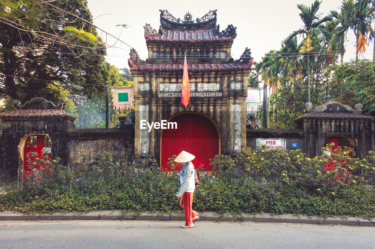 Person in asian style conical hat against traditional building