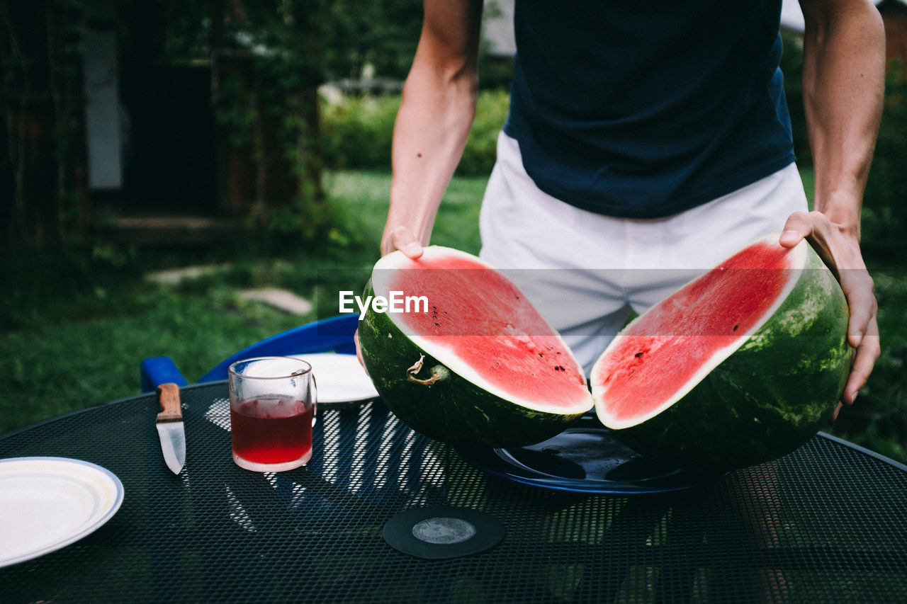 Midsection of man holding watermelon at table