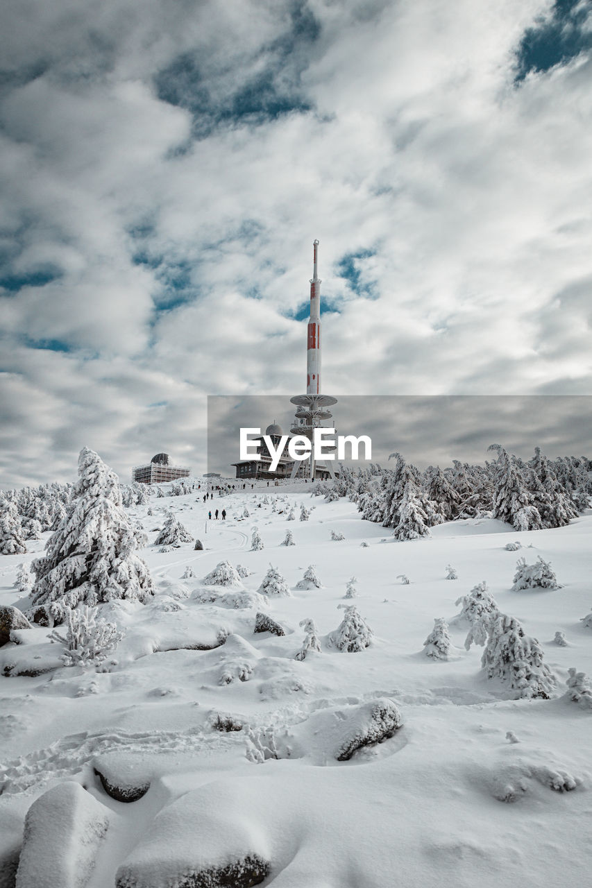 VIEW OF TOWER ON SNOW COVERED MOUNTAIN AGAINST SKY