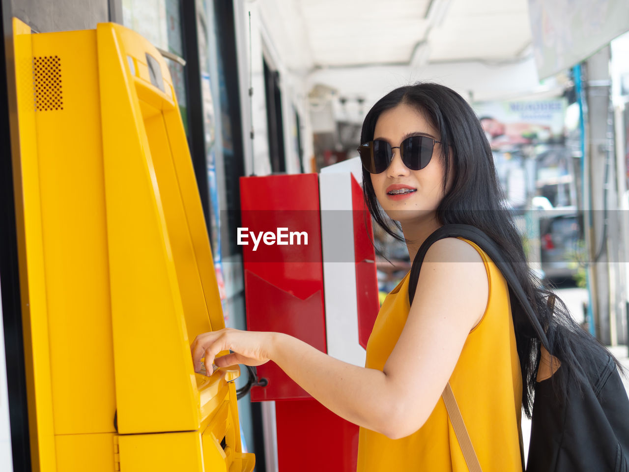 Smiling young woman using atm machine in city