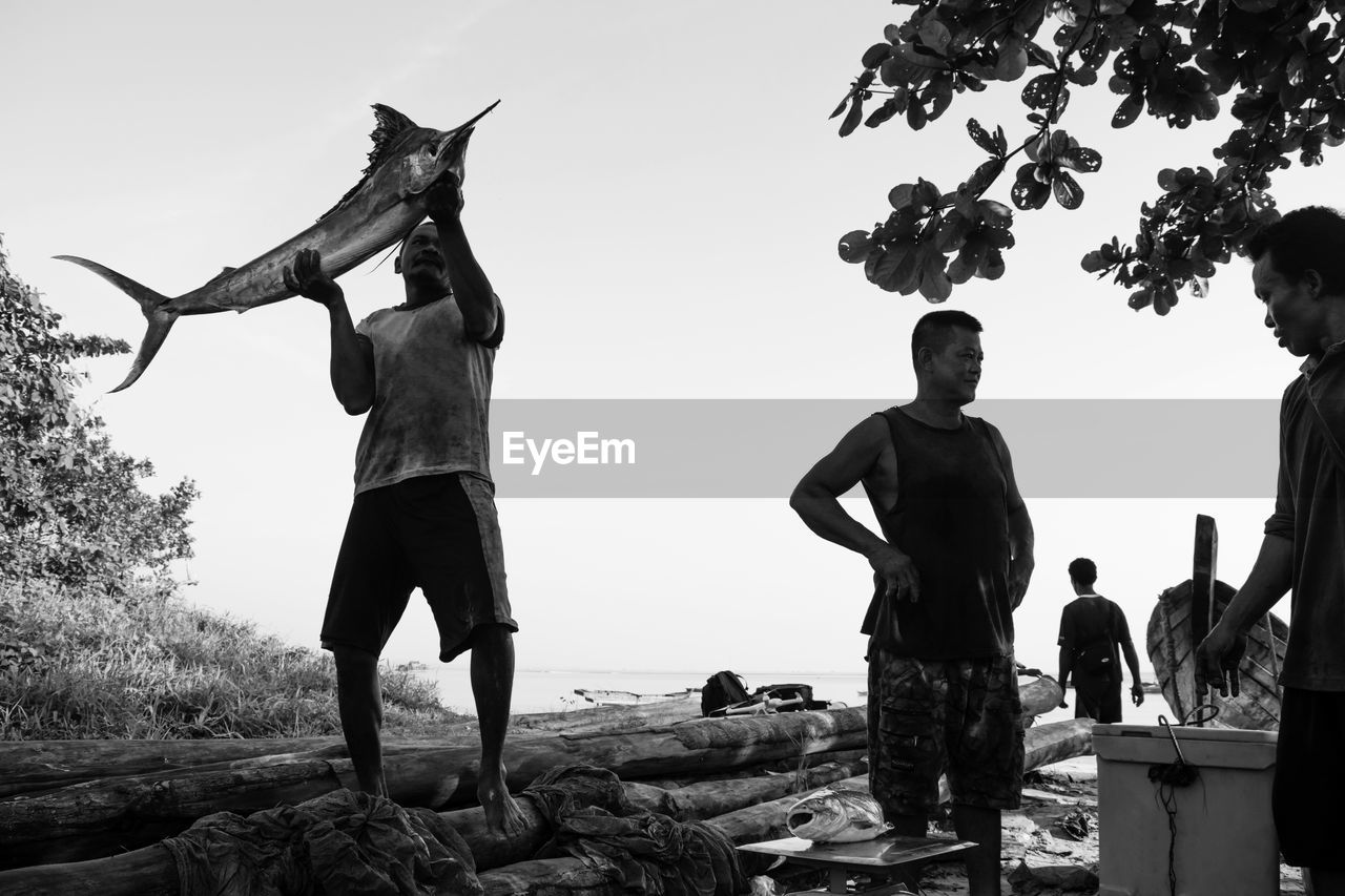 Man with catch of fish against clear sky