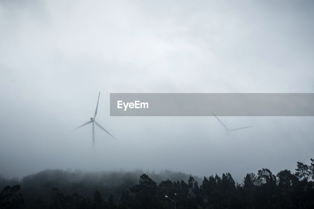 Low angle view of windmill on field during foggy weather