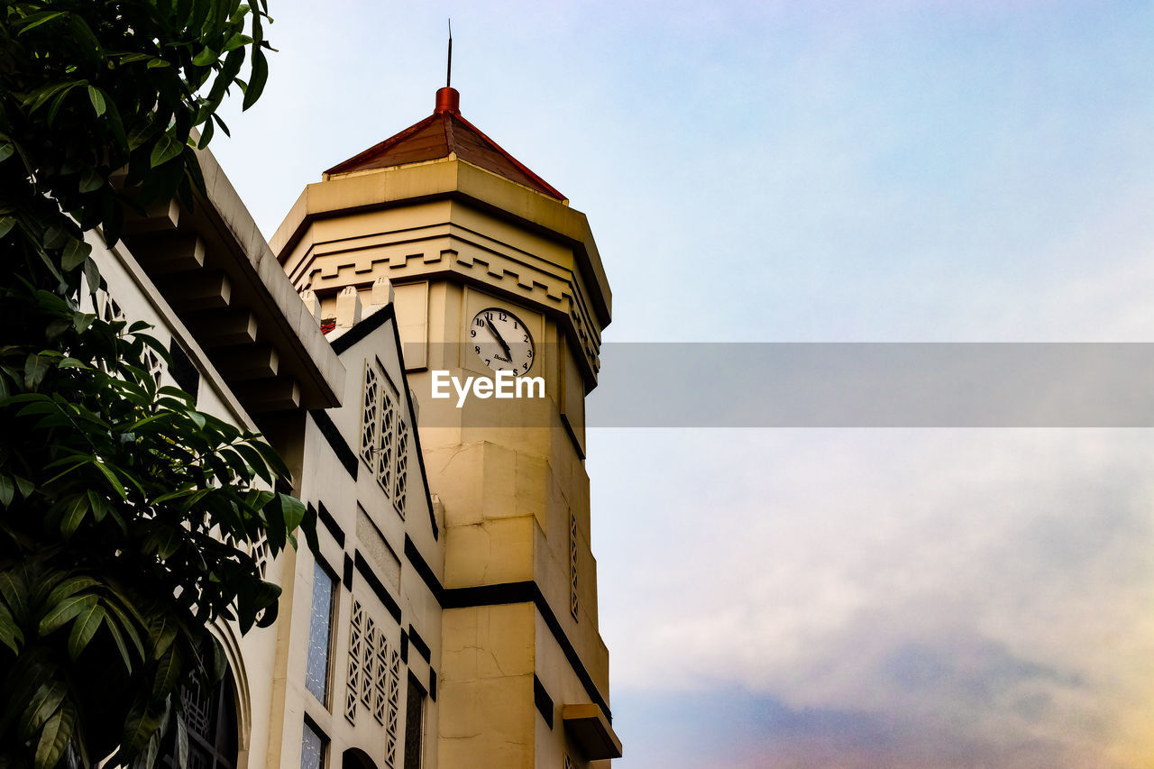 LOW ANGLE VIEW OF CLOCK TOWER AMIDST BUILDING AGAINST SKY