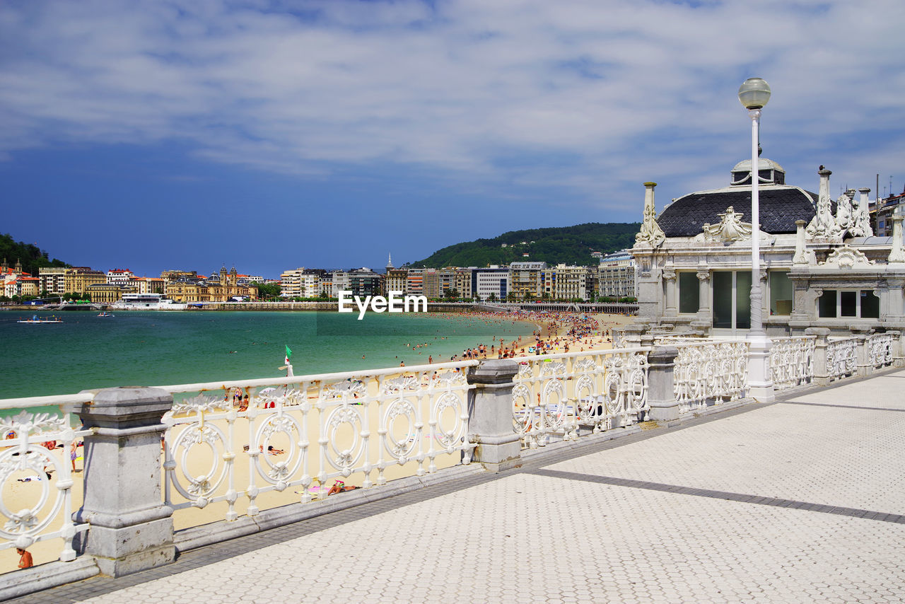 View of buildings by sea against cloudy sky