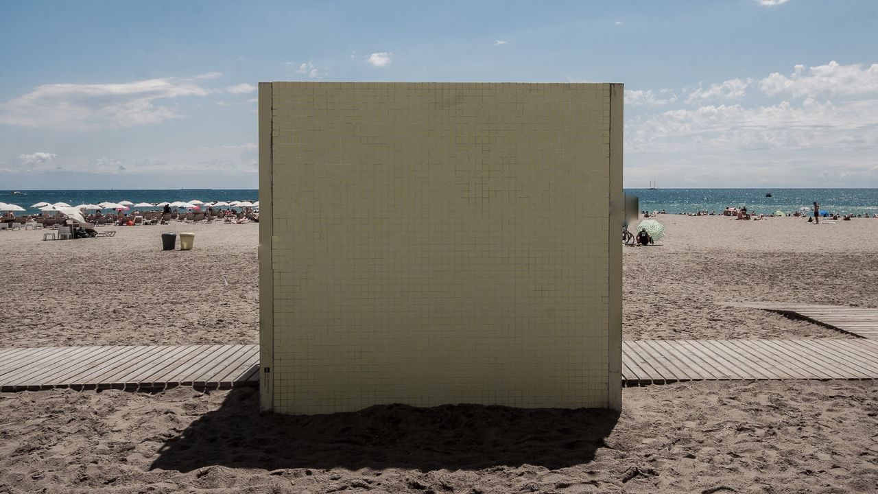 PEOPLE ON BEACH BY SEA AGAINST SKY