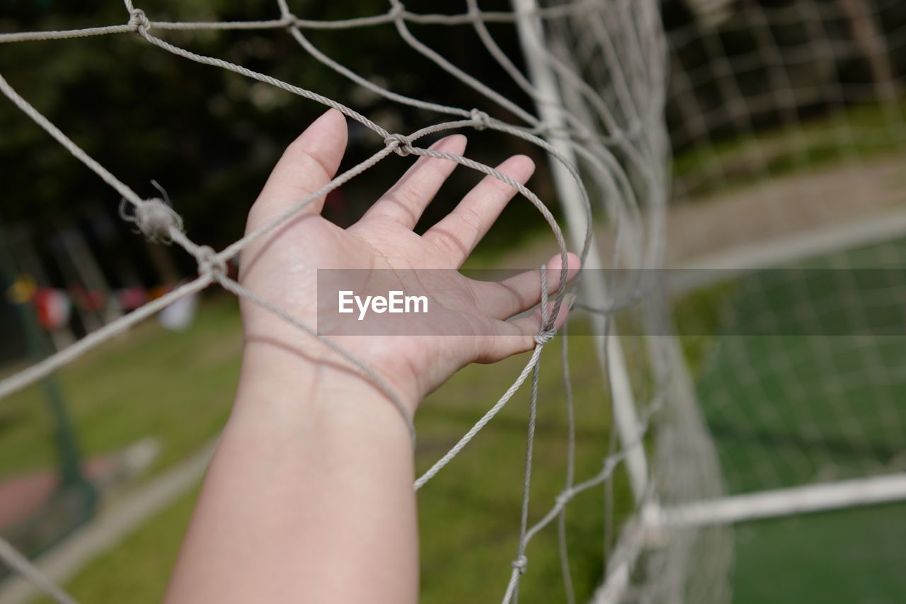 Close-up of hand holding goal post net