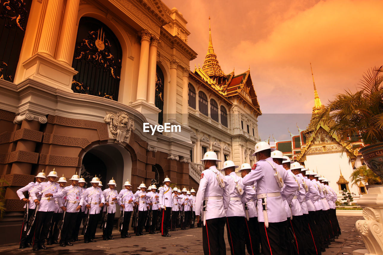 Army soldiers standing by historic building during sunset