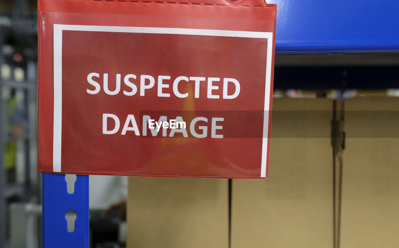 A shelf with packages and a sign saying suspected damage