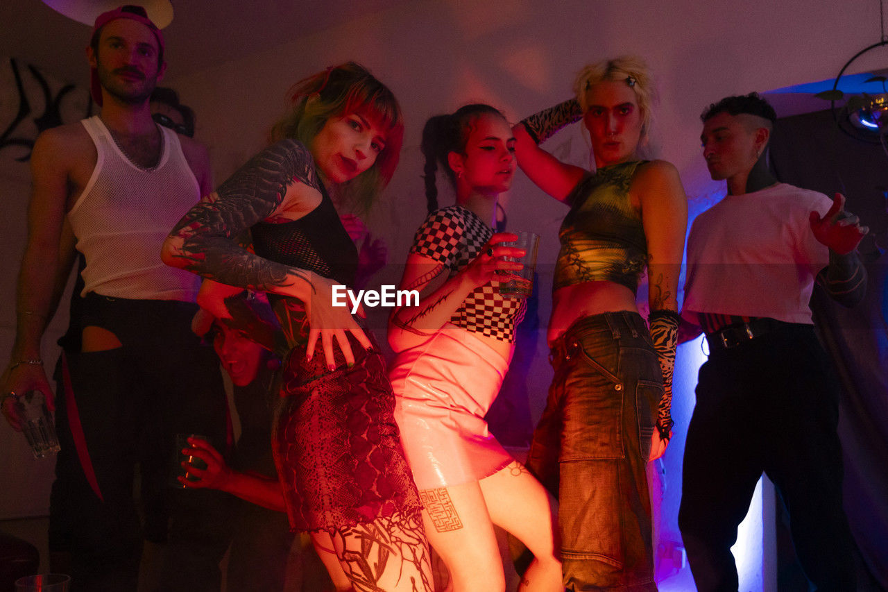 Portrait of non-binary friends dancing in illuminated nightclub