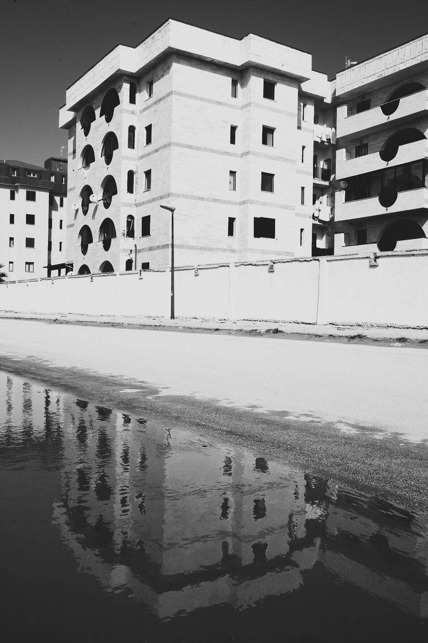 REFLECTION OF BUILDING IN SWIMMING POOL AGAINST SKY