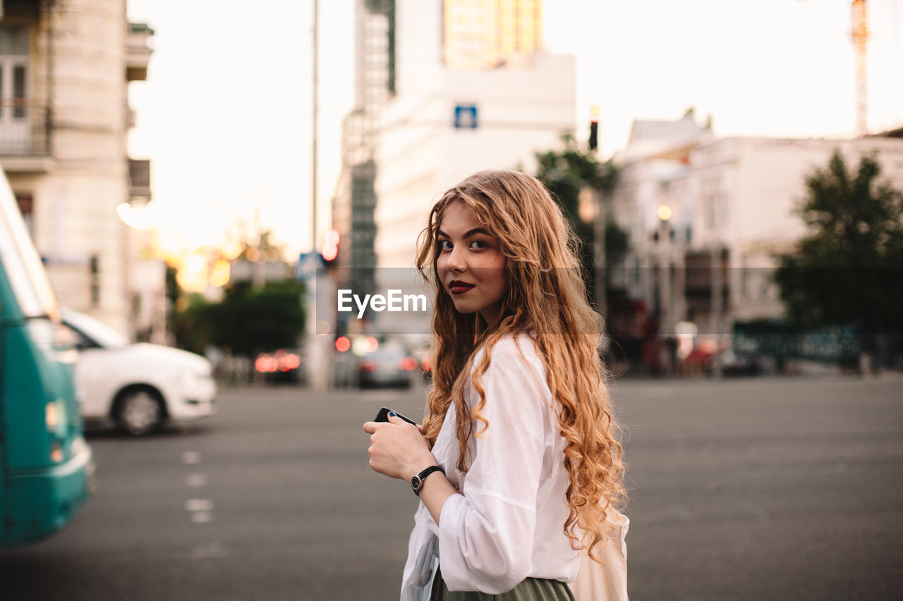 Portrait of serious young woman standing on street in city