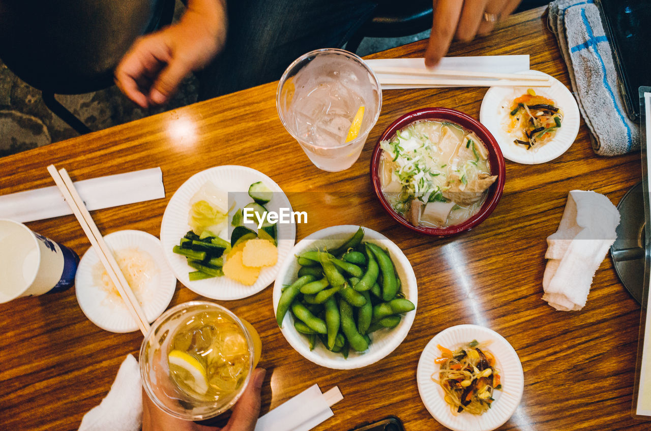 Cropped hands of people with food and drink on wooden table