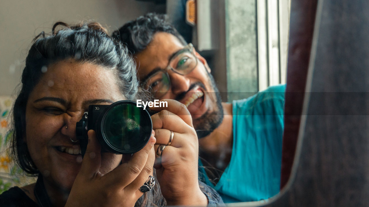 PORTRAIT OF MAN PHOTOGRAPHING WOMAN WEARING CAMERA