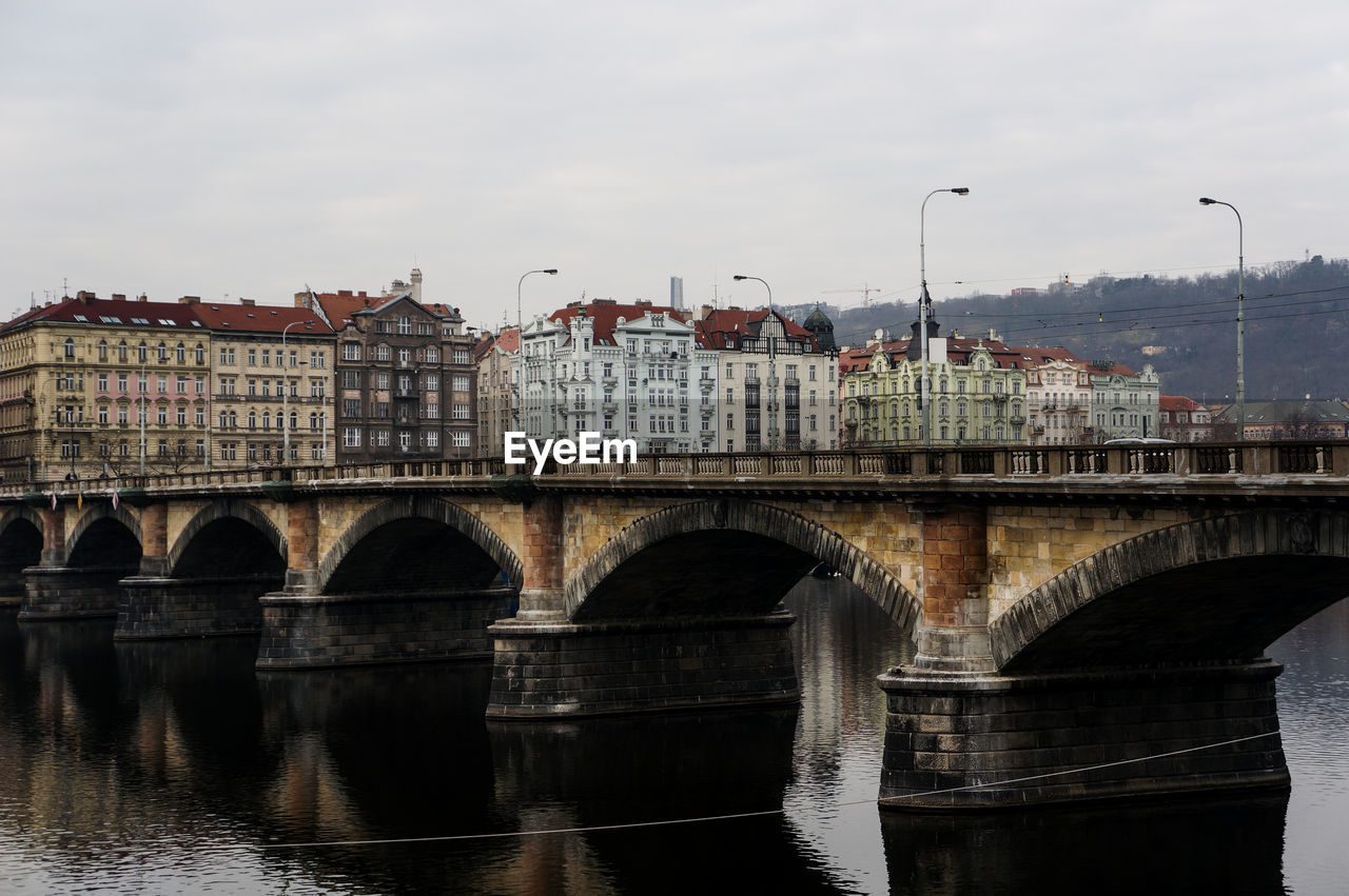 Bridge over river in city against sky