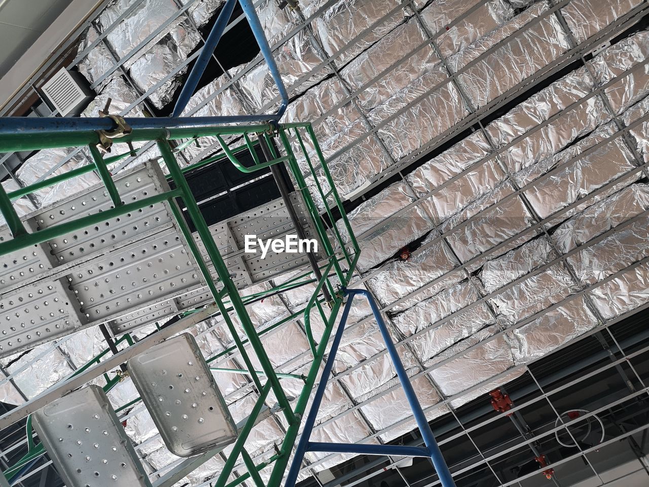 LOW ANGLE VIEW OF ABANDONED BUILDING SEEN THROUGH METAL WALL