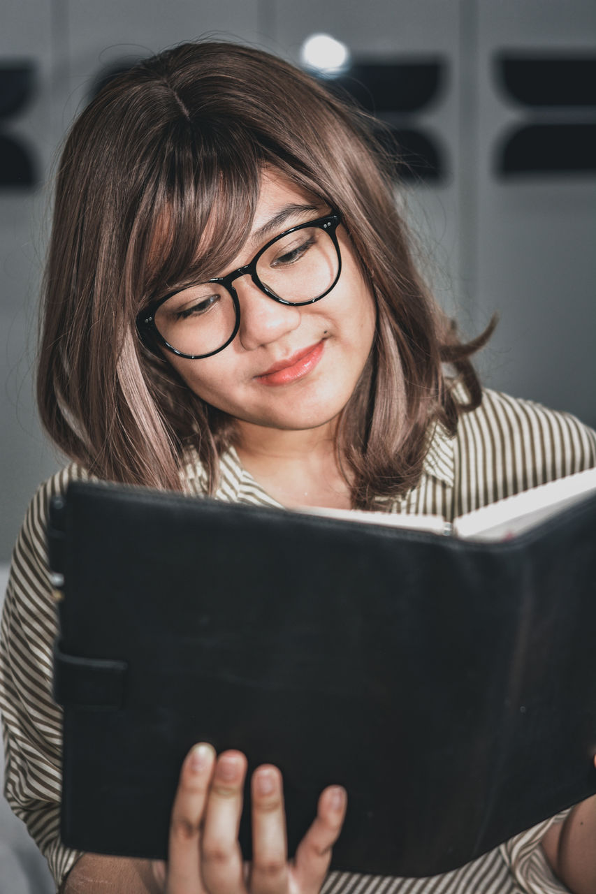 Portrait of a young girl reading a book with leather cover