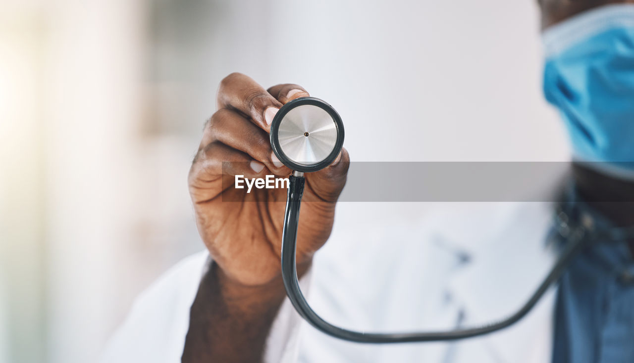 midsection of doctor holding stethoscope at clinic