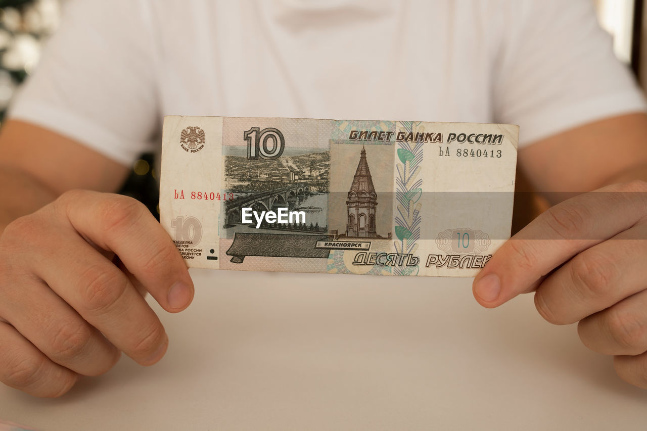 A close-up man holds in his hands an unfolded bill with a face value of 10 rubles. russian money.
