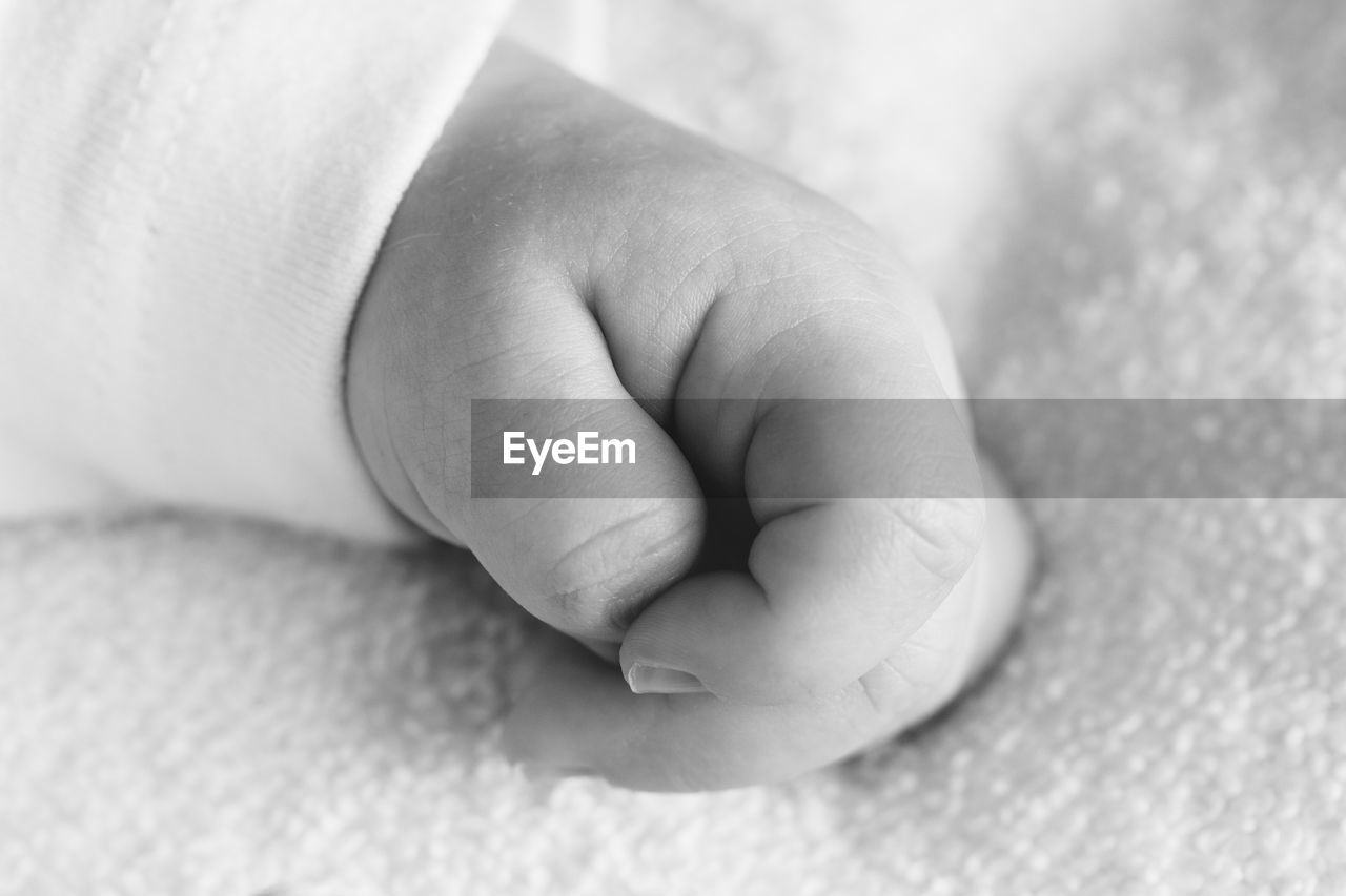 Cropped hand of baby on bed