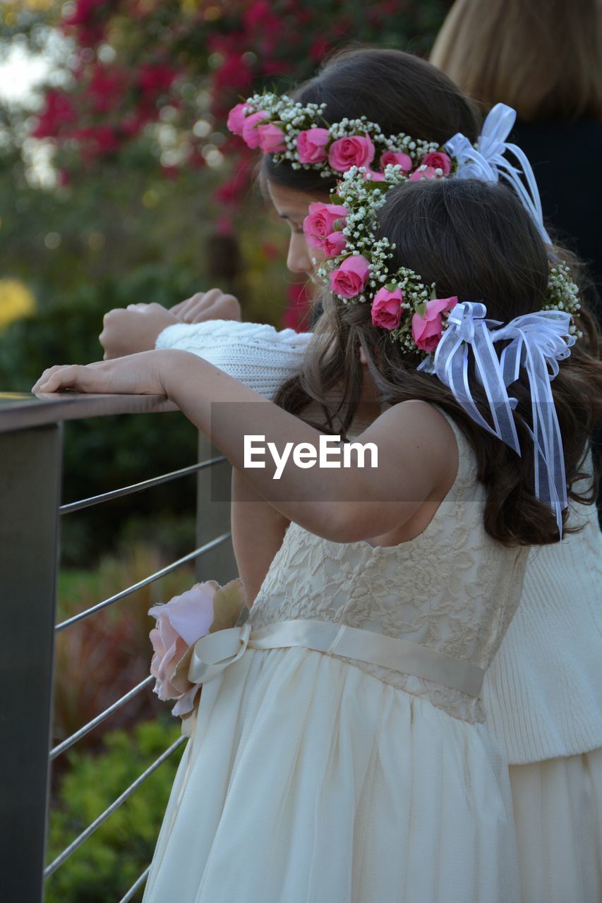 Girls wearing flowers standing by railing