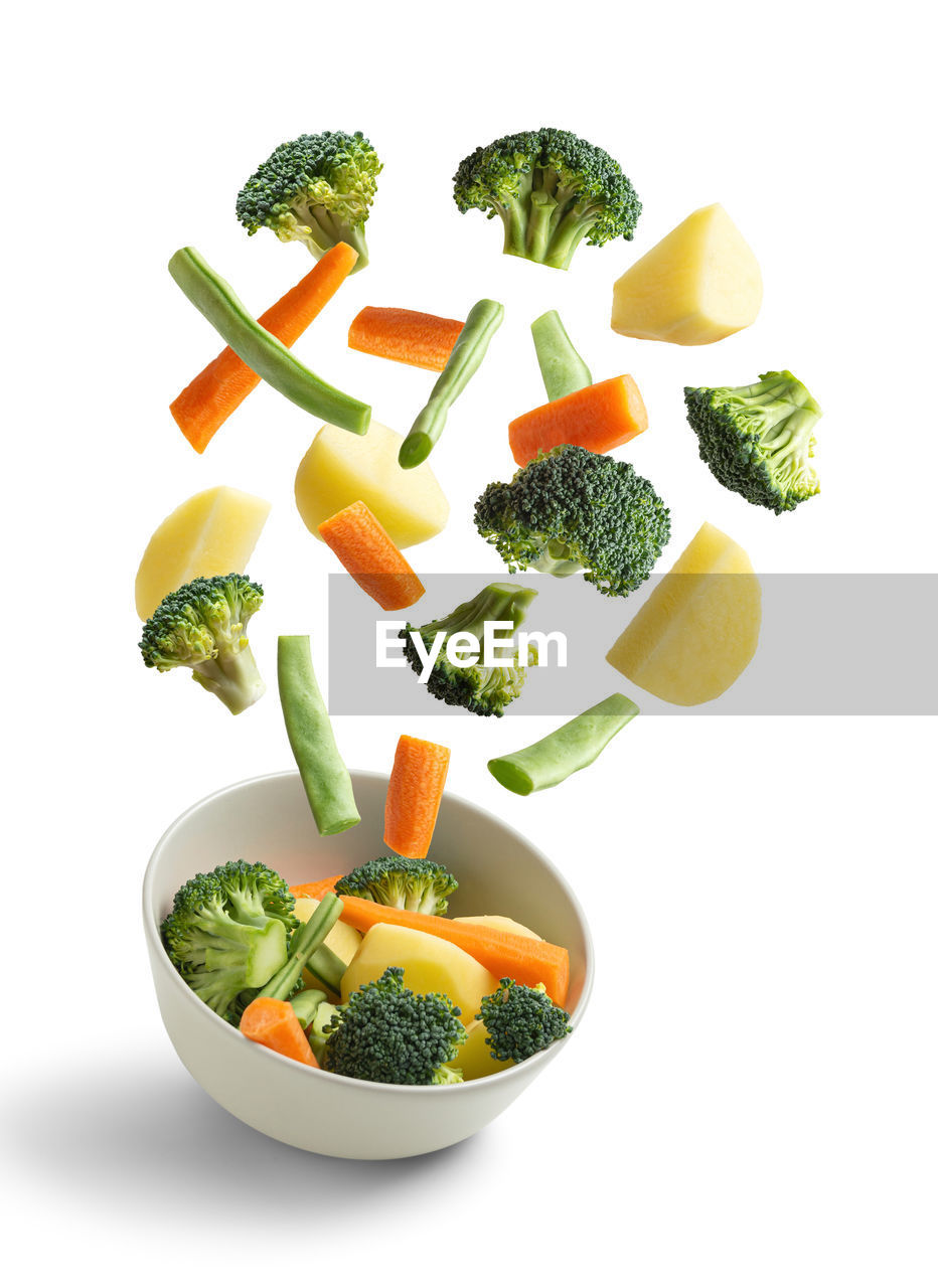 Boiled vegetables flying on white background. creative concept
