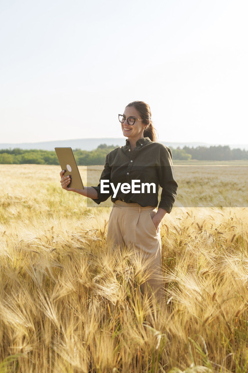 Smiling businesswoman talking on video call through tablet pc at farm