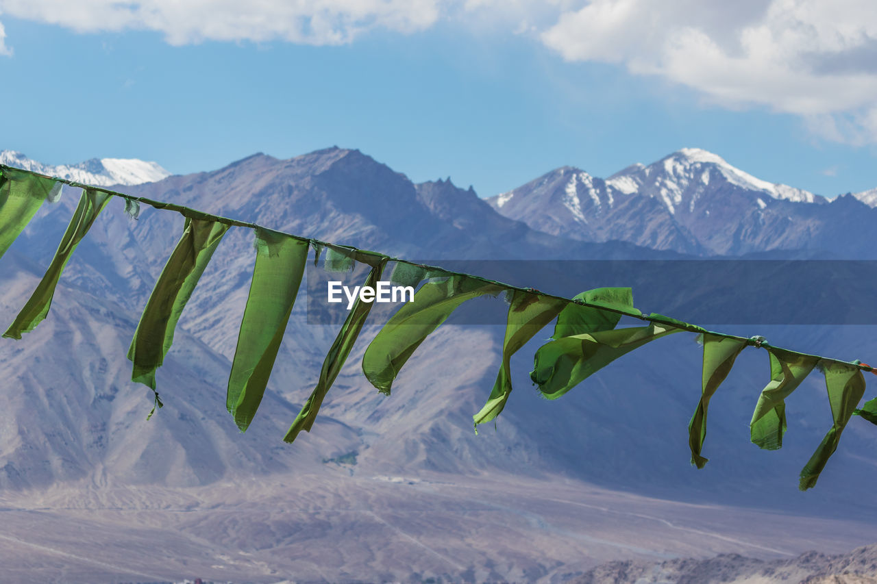 Close-up of prayer flags waving against snowcapped mountains and sky