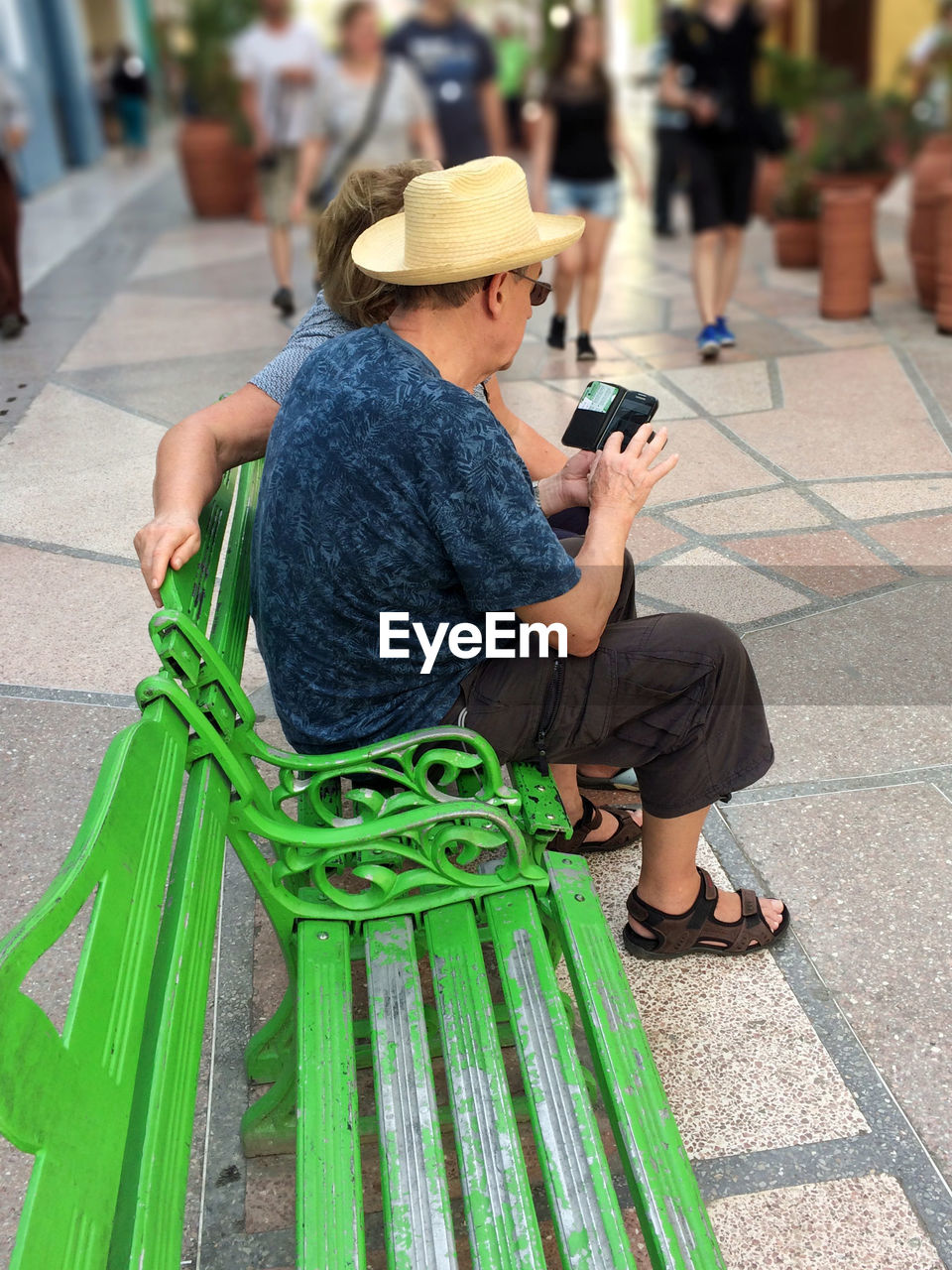 WOMAN HOLDING MOBILE PHONE WHILE STANDING ON SIDEWALK