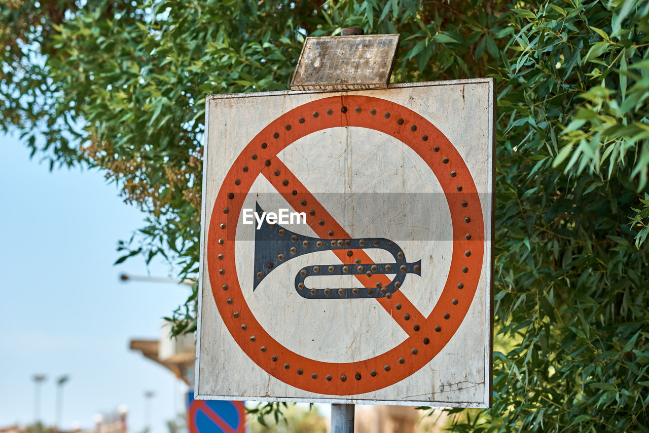 Close-up of no honk sign against trees