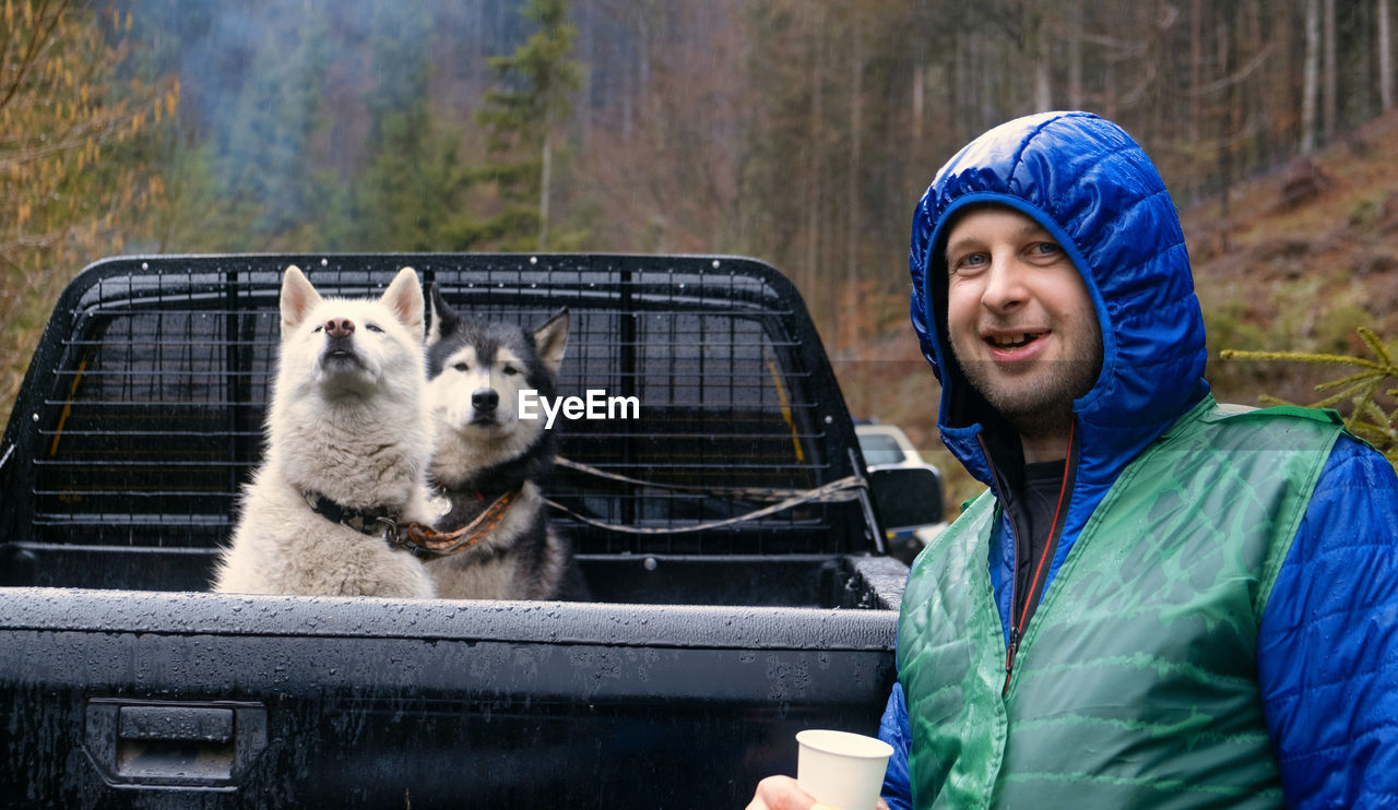 Traveler with siberian tow beautiful husky dog in the wagon car. person with dog in the forset