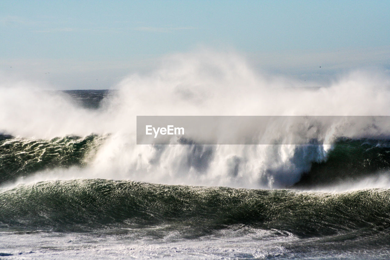 Scenic view of waves breaking against sea