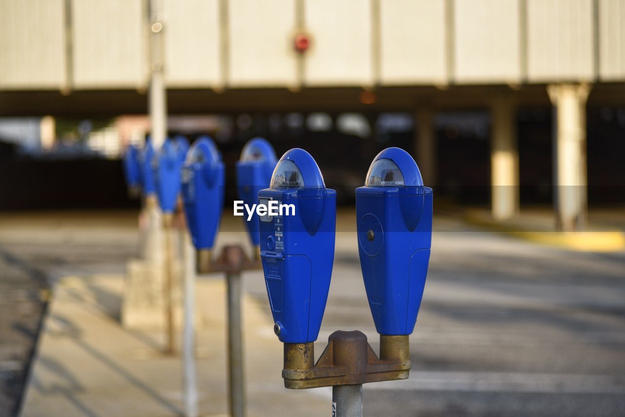 Close-up of parking meters on street against building