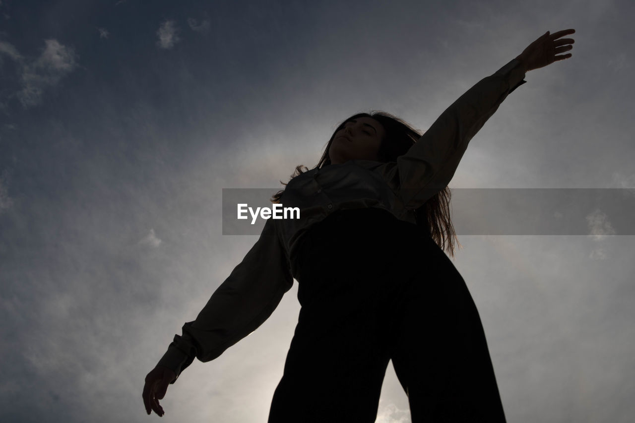 Low angle view of woman standing against sky