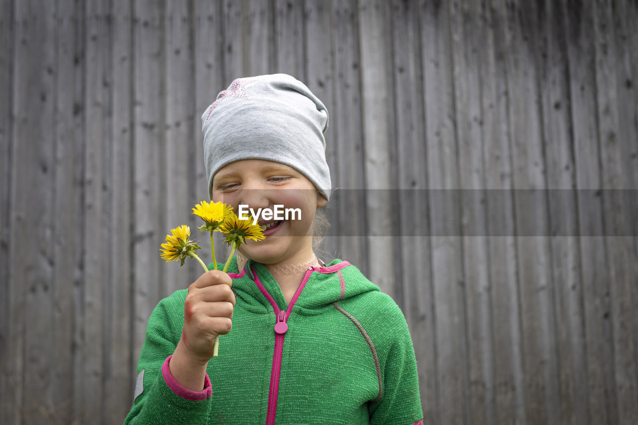 Smiling boy holding flower standing outdoors