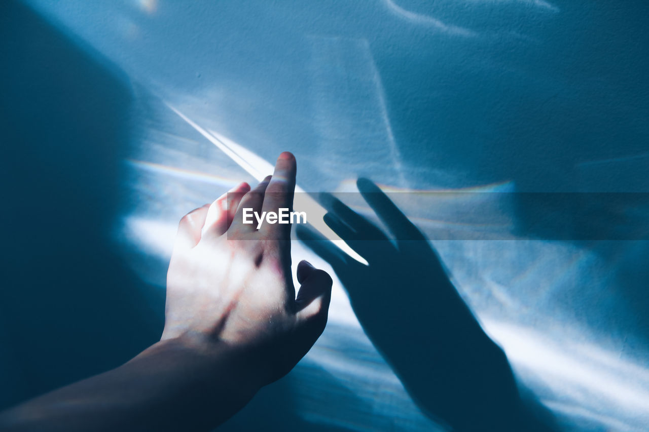 Cropped hand of woman touching rainbow on wall