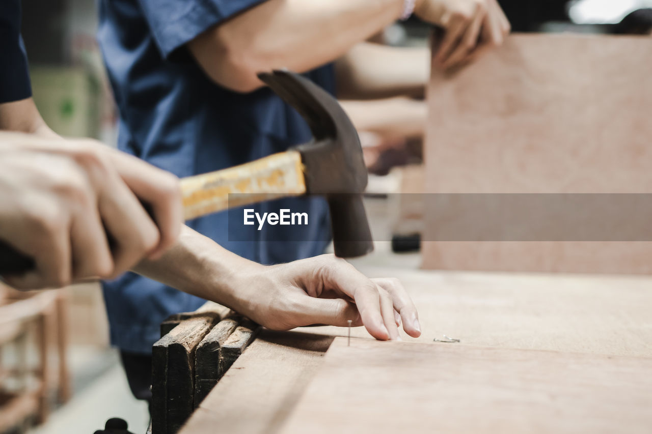 CLOSE-UP OF MAN WORKING ON WOODEN TABLE