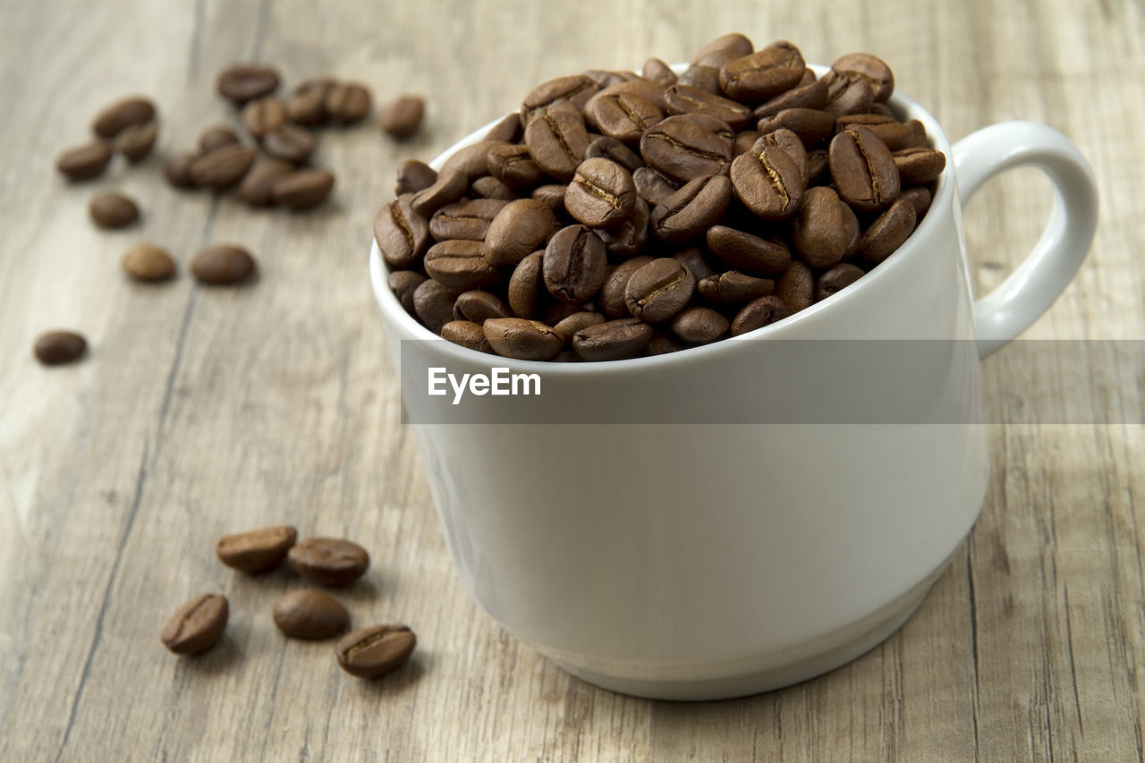 Close-up of coffee beans in mug on table