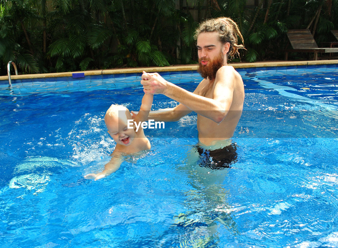 High angle view of father playing with daughter in swimming pool