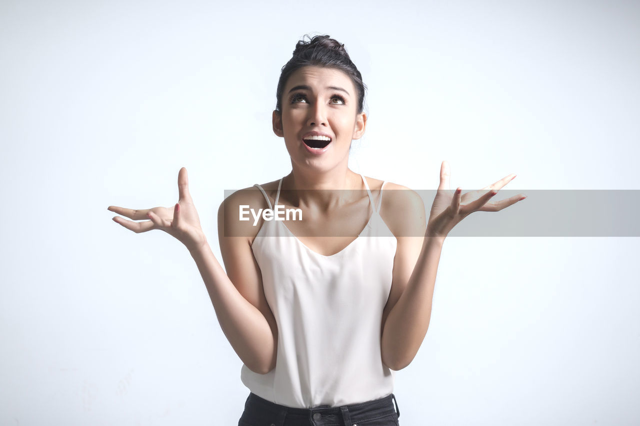 Angry young woman standing against white background