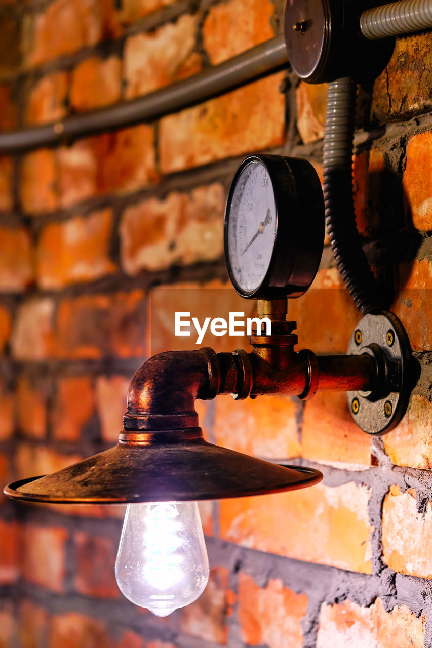 Close-up of electric lamp on brick wall