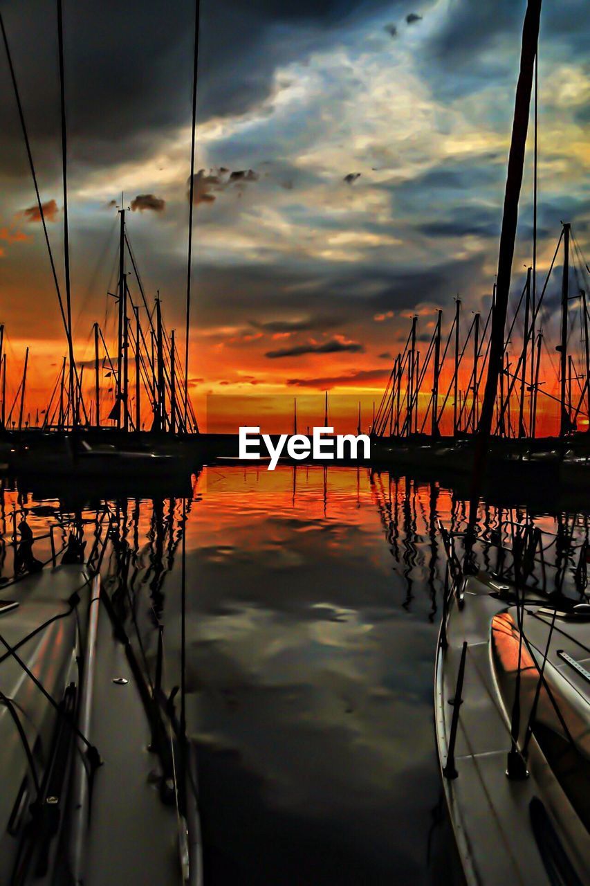 Silhouettes of sailing boats in marina during sunset