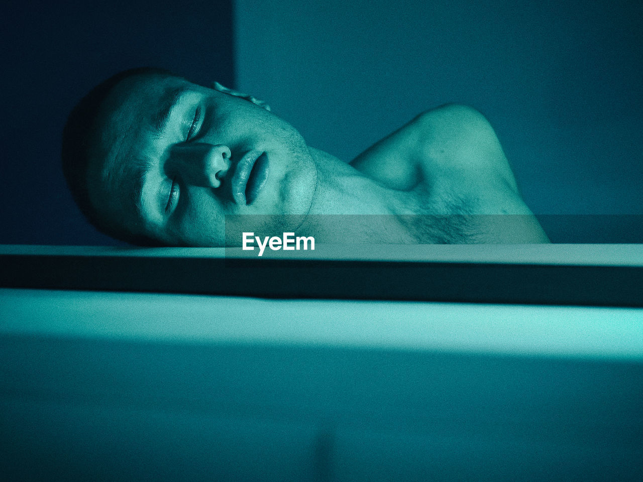 Close-up of shirtless young man sleeping in bathtub at home
