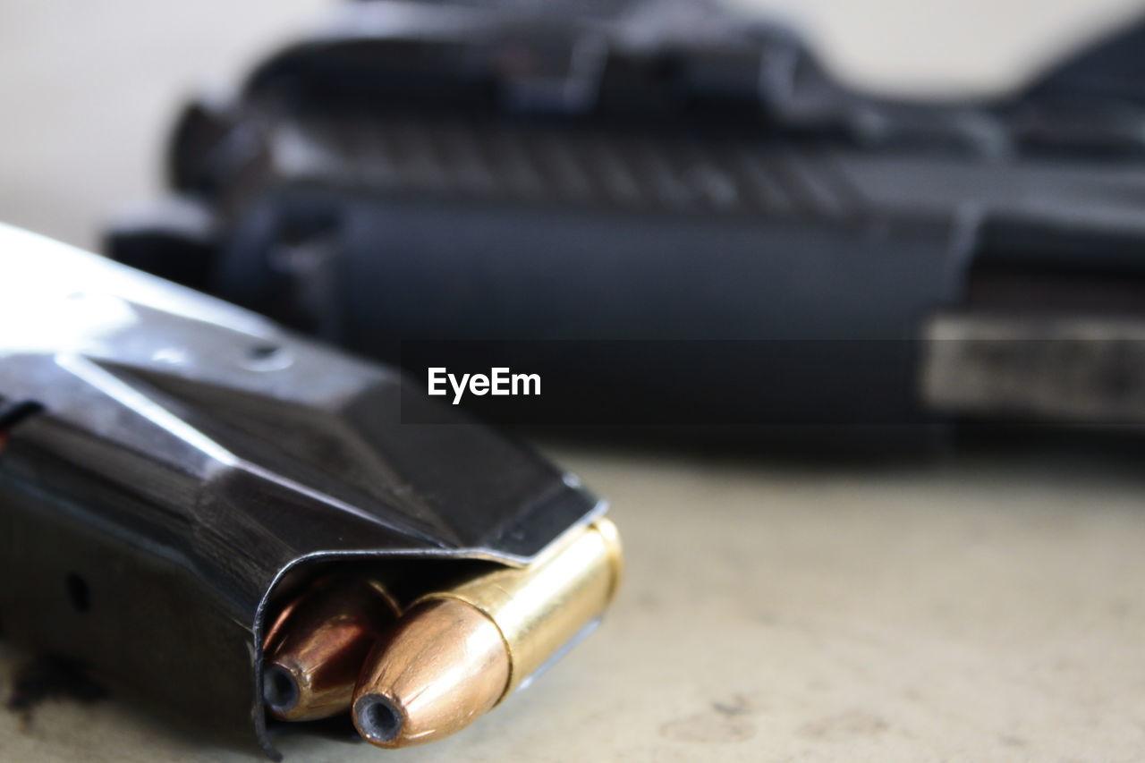 Close-up of magazine with bullets by gun on table